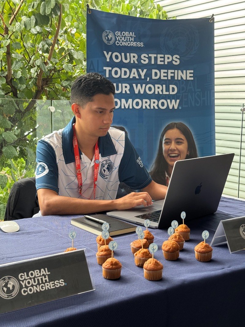 Mau working on a laptop at a Global Youth Congress table